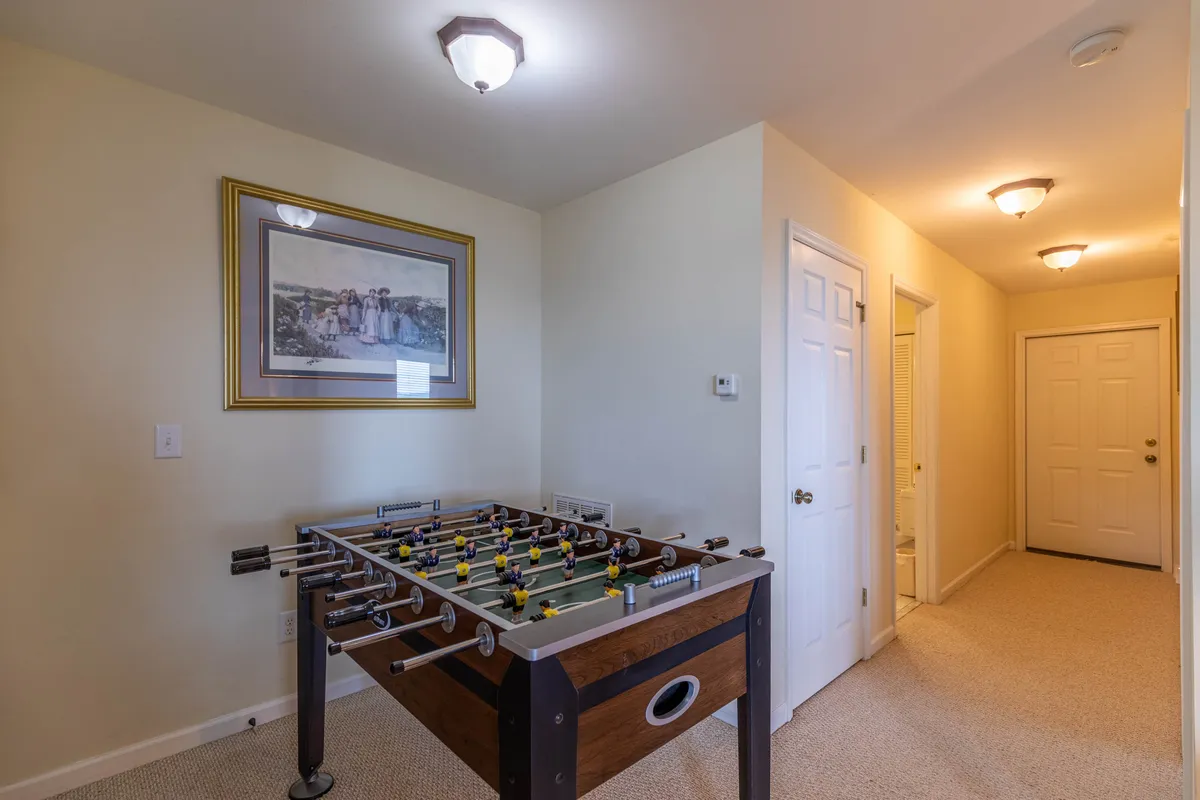 A family-friendly recreation room focusing on a foosball table, with framed artwork and a visible doorway. The space exudes a playful, energetic mood, ideal for lively gatherings of all ages.