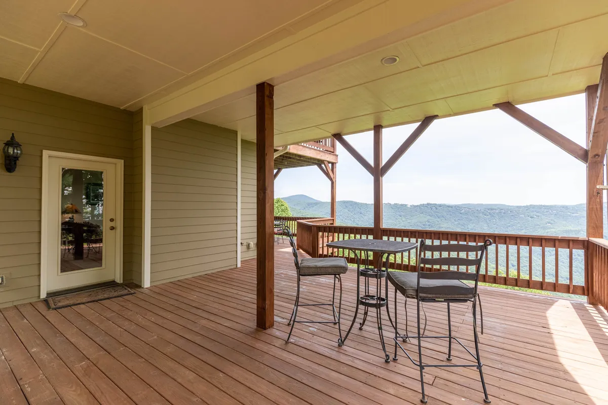 An inviting outdoor table and chairs are set on a deck, with sweeping mountain views stretching into the distance. The space feels peaceful and secluded, perfect for relaxing, sharing meals, or gathering with friends while immersed in nature.