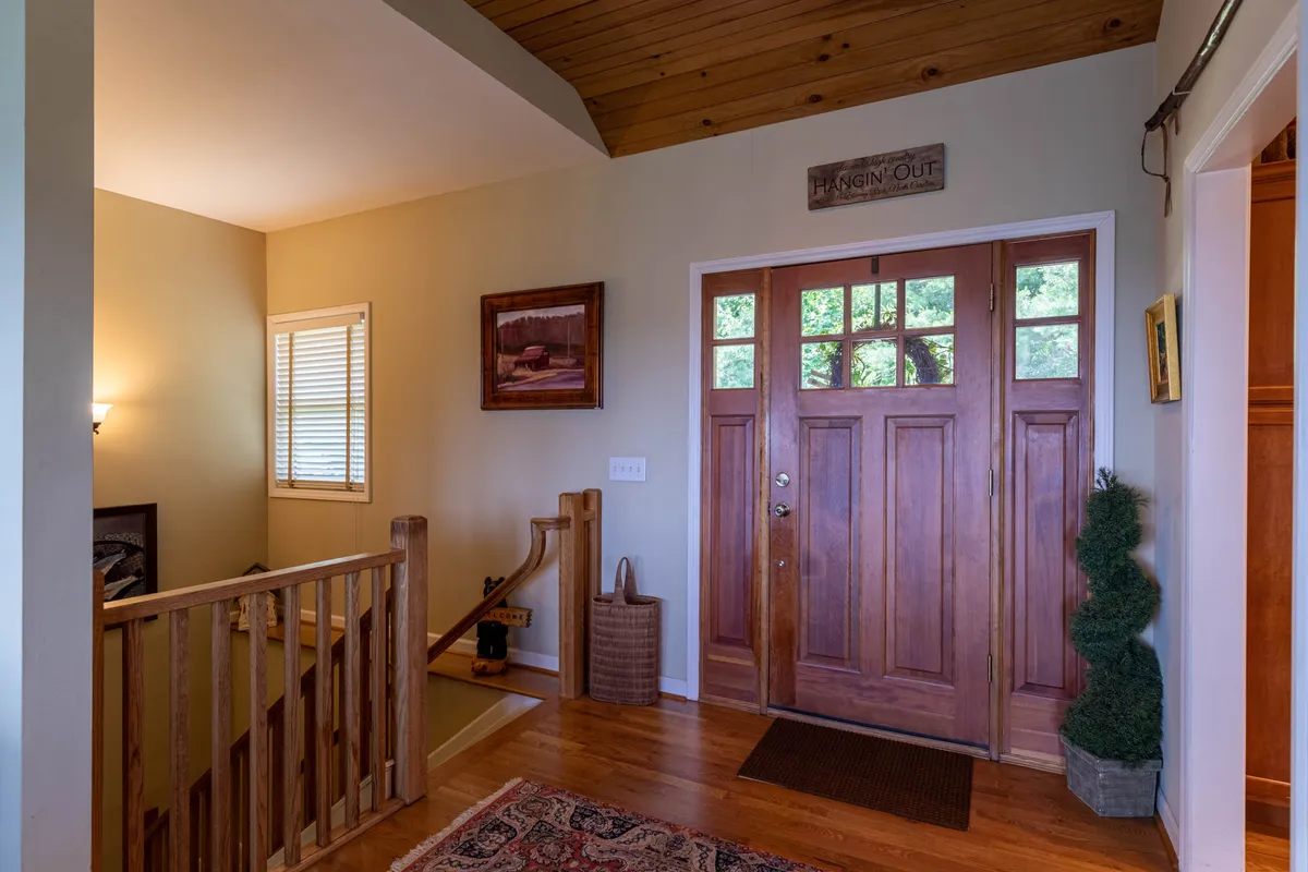 A welcoming entry area with a front door, staircase, tasteful artwork, and a decorative rug. Subtle touches like a topiary and natural lighting make the space inviting and accessible for guests of all ages.