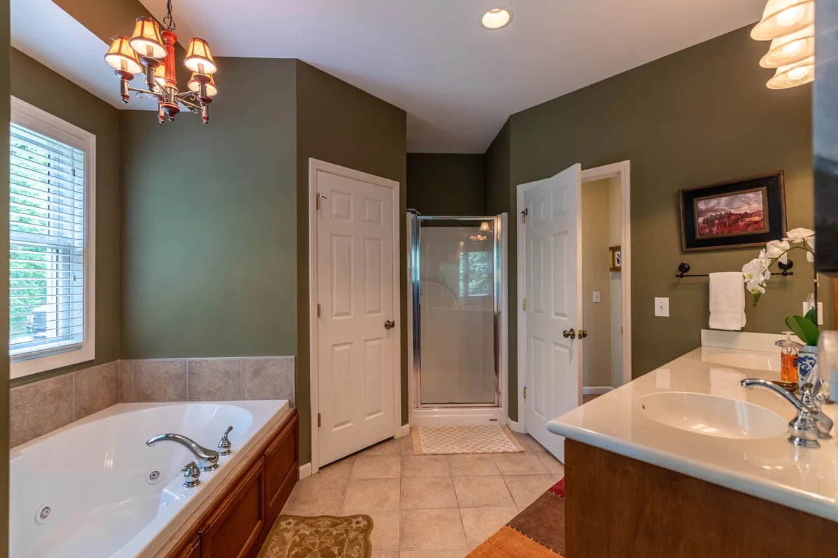 A tranquil bathroom featuring a large bathtub, sink area, shower enclosure, and a window letting in natural light. The space is designed for relaxation, offering a spa-like retreat after a day of mountain adventures.